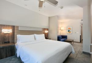 a bedroom with a large white bed and a blue chair at Holiday Inn Express & Suites North Dallas at Preston, an IHG Hotel in Dallas