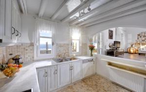 biała kuchnia ze zlewem i oknem w obiekcie Luxurious Villa in Mykonos with Pool w mieście Agios Ioannis
