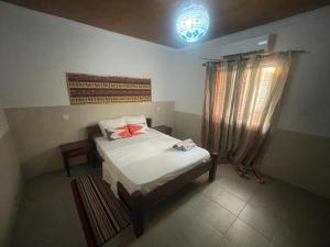 ein kleines Schlafzimmer mit einem Bett und einem Fenster in der Unterkunft RALUX house in São Tomé
