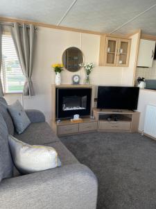 ein Wohnzimmer mit einem Sofa und einem Flachbild-TV in der Unterkunft ParkDean cherry tree holiday park in Great Yarmouth