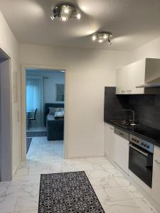 a kitchen with white cabinets and a living room at Apartment Rot-Kreuz in Bad Säckingen