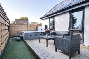 Hoxne Cottages - Sunflower Cottage with private hot tub في يورك: فناء مع أريكة وطاولة مع الزهور