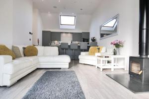 Hoxne Cottages - Sunflower Cottage with private hot tub في يورك: غرفة معيشة مع كنبتين بيضاء ومدفأة +3 صور