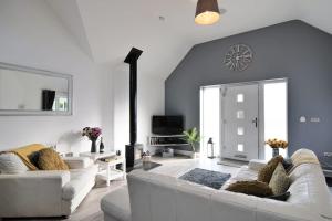 Hoxne Cottages - Sunflower Cottage with private hot tub في يورك: غرفة معيشة مع كنبتين بيضاء وتلفزيون