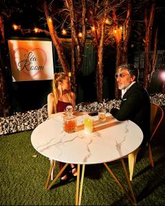 un homme et une femme assis à une table dans l'établissement Léa Room - Gîte Romantique - Jacuzzi, à Bourguébus