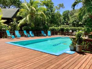 a swimming pool on a wooden deck with blue chairs at Tropical Treehouse in Sandy Bay