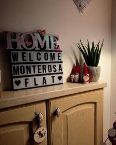 a home welcome sign on top of a cabinet at Appartamento vista Monte Rosa, giardino in Residence Walser a 10minuti da Macugnaga - MONTEROSAFLAT in Vanzone