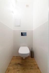 a white toilet in a white bathroom with a wooden floor at Apartament Gersona 4 in Bydgoszcz