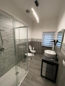 La salle de bains est pourvue de 2 toilettes et d'une douche en verre. dans l'établissement Foresteria Opera B&b, à Rovato