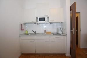 een witte keuken met een wastafel en een magnetron bij Ferienwohnung in Freilassing