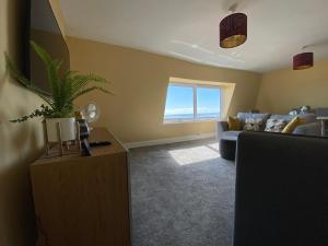 a living room with a couch and a table with a plant at Sky Lounge - Beachfront top floor apartment with stunning veiws in Kent