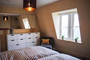 ein Schlafzimmer mit einem Bett, einer Kommode und einem Fenster in der Unterkunft Sky Lounge - Beachfront top floor apartment with stunning veiws in Kent