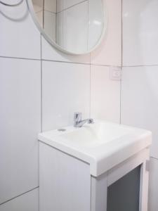 Baño blanco con lavabo y espejo en Steve's House en Puerto Iguazú