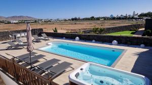 a swimming pool on a patio with chairs and an umbrella at Villa Little Star in Playa Blanca