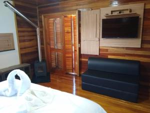 a bedroom with a bed and a flat screen tv at Sítio Passo do Carro in São Francisco de Paula