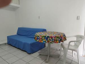 Cette chambre comprend un lit avec une table et une chaise. dans l'établissement Seu Apto na Praia da Costa 13 Barato Completo TV Geladeira Fogão Ar Cond Local Excelente Centro, à Vila Velha