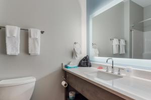 a bathroom with a sink and a toilet and a mirror at SureStay Plus Hotel by Best Western Highland Poughkeepsie in Highland +17 photos