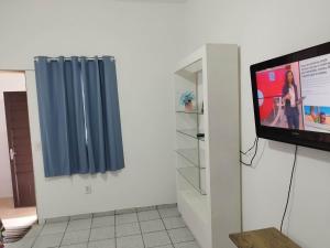 Cette chambre dispose d'une télévision et d'un rideau bleu. dans l'établissement Seu Apto na Praia da Costa 13 Barato Completo TV Geladeira Fogão Ar Cond Local Excelente Centro, à Vila Velha