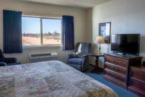 a hotel room with a bed and a flat screen tv at Lighthouse Inn - Two Rivers in Two Rivers