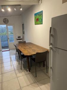 eine Küche mit einem Holztisch und Stühlen sowie einem Kühlschrank in der Unterkunft Chez KAKINE in La Plaine des Palmistes