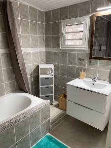 y baño con bañera y lavamanos. en Chez KAKINE, en La Plaine-des-Palmistes