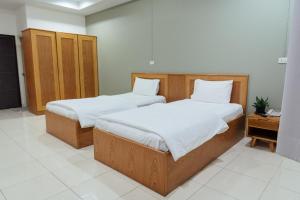 two twin beds in a room with a tv at JJ Palace เจเจ พาเลซ in Ban Si Than