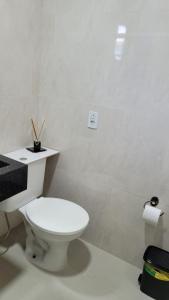 a white bathroom with a toilet and a shelf on the wall at Marques Home in Porto Belo