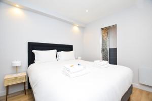 a white bedroom with a large white bed and a window at Charming appart-6P-Sacré-Cœur Pigalle- PARIS 9 in Paris