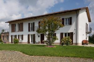 une maison blanche avec un arbre devant dans l'établissement Casa Monteverdi, à Vinchio