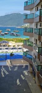um edifício com piscina junto ao oceano em 2 QUARTOS a 50m PRAIA dos Anjos em Condomínio Club com PISCINA, estacionamento e portaria 24h - Área de lazer 3000m, wi-fi 450MB, churrasqueira e cozinha completa em Arraial do Cabo