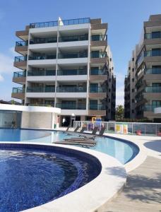 uma piscina em frente a um edifício em 2 QUARTOS a 50m PRAIA dos Anjos em Condomínio Club com PISCINA, estacionamento e portaria 24h - Área de lazer 3000m, wi-fi 450MB, churrasqueira e cozinha completa em Arraial do Cabo