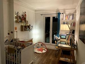 um pequeno quarto com um berço e uma secretária com um computador portátil em Appartement familial douillet chez Anja & Charles em Paris