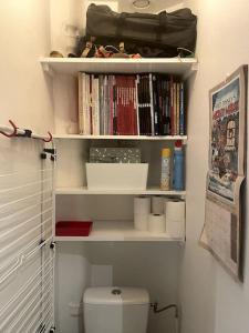 uma casa de banho com WC e prateleiras com livros em Appartement familial douillet chez Anja & Charles em Paris
