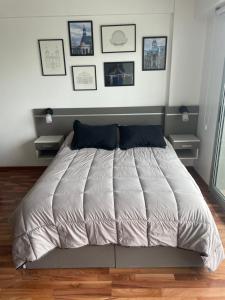 Metropolitan Highline Apartments في بوينس آيرس: سرير في غرفة نوم مع صور على الحائط