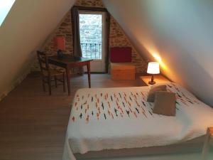 ein Schlafzimmer mit einem Bett und einem Schreibtisch im Dachgeschoss in der Unterkunft Le Four de La Jugie in Le Lonzac