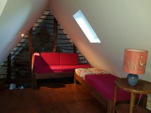 ein Wohnzimmer mit einem roten Sofa im Dachgeschoss in der Unterkunft Le Four de La Jugie in Le Lonzac