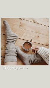 eine Person in grauen Socken mit einer Tasse Kaffee auf einem Holzboden in der Unterkunft Porumbacu Treehouse in Porumbacu de Sus