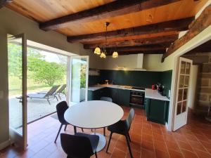 una cocina con armarios verdes, mesa y sillas en Maison d'amis du Manoir de Saint-Bazile en Saint-Bazile-de-Meyssac