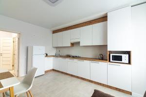 a white kitchen with white cabinets and a table at NEW Apartment on Zhasmynova Street 5b in Lviv