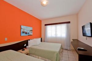 a hotel room with two beds and a flat screen tv at Hotel Areia de Ouro in Natal