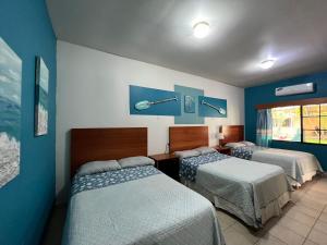 two beds in a room with blue walls at Hotel Viña del Mar Omoa in Omoa
