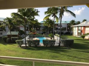 a view of a yard with a pool and palm trees at Crystal Beach, vue mer, accès direct plage et piscine, clim in Sèze
