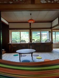 um quarto com uma mesa, cadeiras e janelas em Tanehachi Farm Guesthouse - Vacation STAY 29709v em Aomori