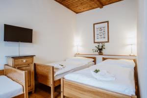a room with two beds and a flat screen tv at Pension Styl in Bedřichov