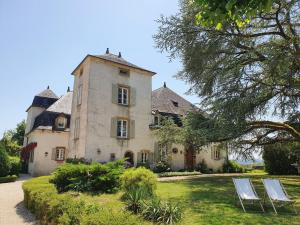 a house with two lawn chairs in front of it at Superbe gîte avec vue sur les vignes, dans le parc d'un manoir du 18ème siècle in Saint-Bazile-de-Meyssac