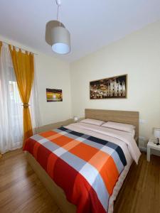 1 dormitorio con 1 cama con manta de rayas naranja y azul en Casa Linda, en Pavia