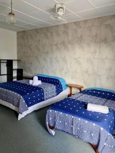 Habitación con 2 camas y sábanas azules y blancas. en Hotel Malinche, en Quepos