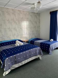 2 camas en una habitación con sábanas azules en Hotel Malinche, en Quepos