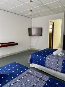 a bedroom with two beds and a tv on the wall at Hotel Malinche in Quepos