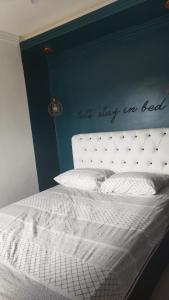 1 dormitorio con cama blanca y pared azul en Apartamentos da praia, en Arraial do Cabo
